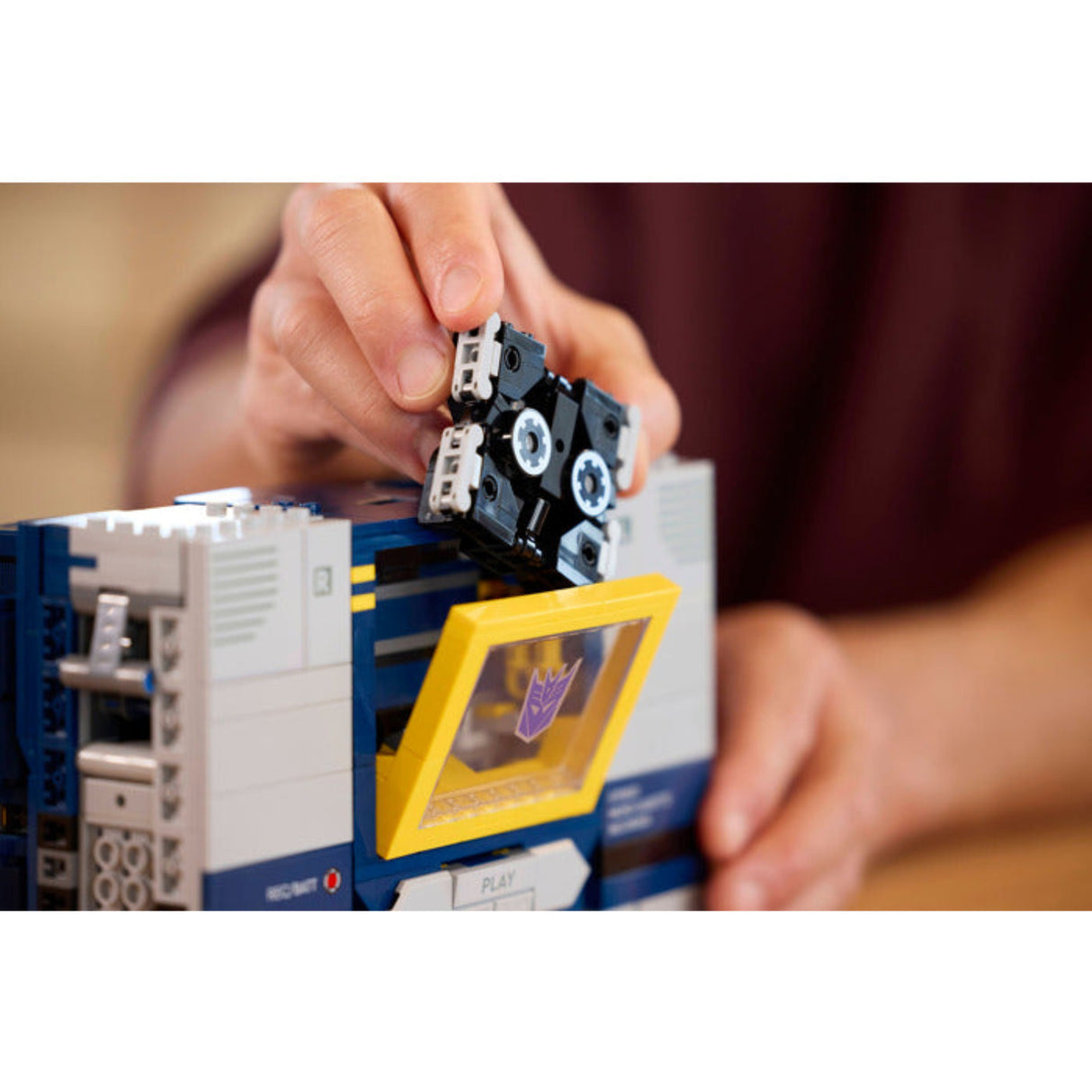 Person assembling a toy robot with a focus on the hands and components.