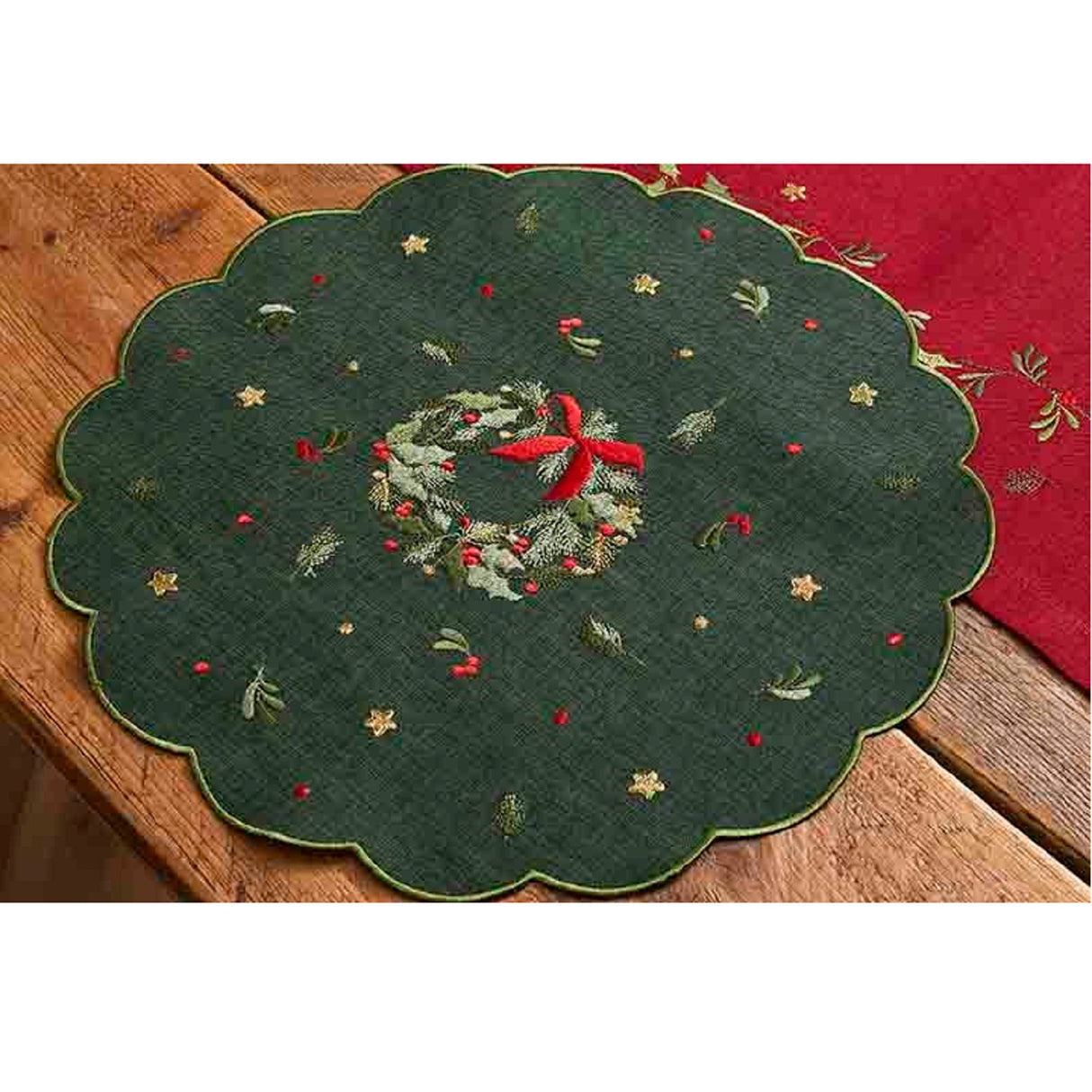 Decorative green table mat with embroidered wreath design on a wooden surface.