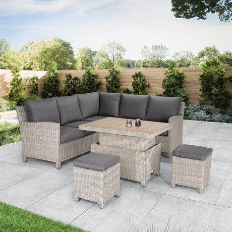 Outdoor furniture set including a corner sofa with gray cushions, a rectangular dining table, and two stools, all made of aluminum and synthetic rattan, set on an outdoor patio.