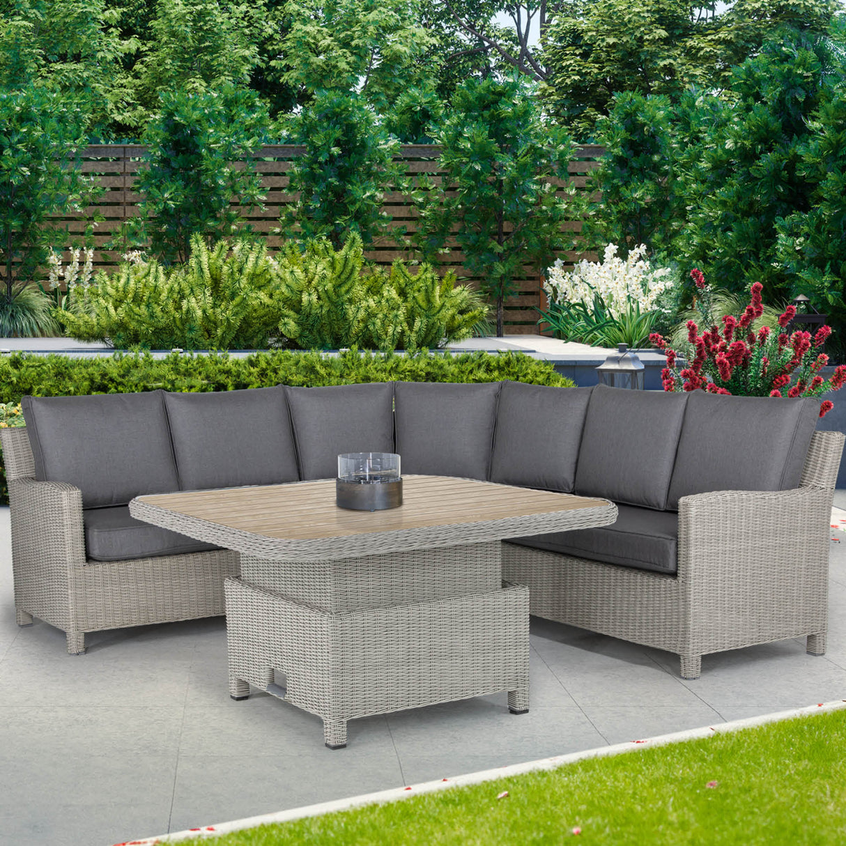 A seven-seater Palma corner sofa with grey cushions and a matching square High/Low table made of synthetic rattan, set on a patio with greenery in the background.