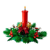 Decorative Christmas arrangement with a red candle, greenery, and berries on a white background