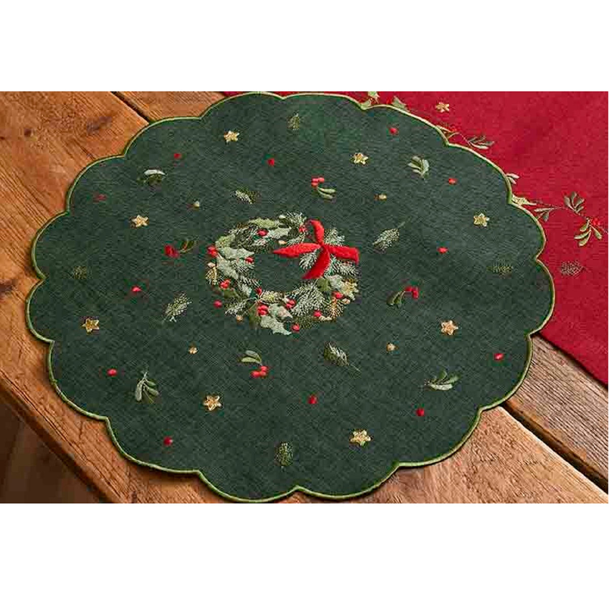Decorative green table mat with embroidered wreath design on a wooden surface.