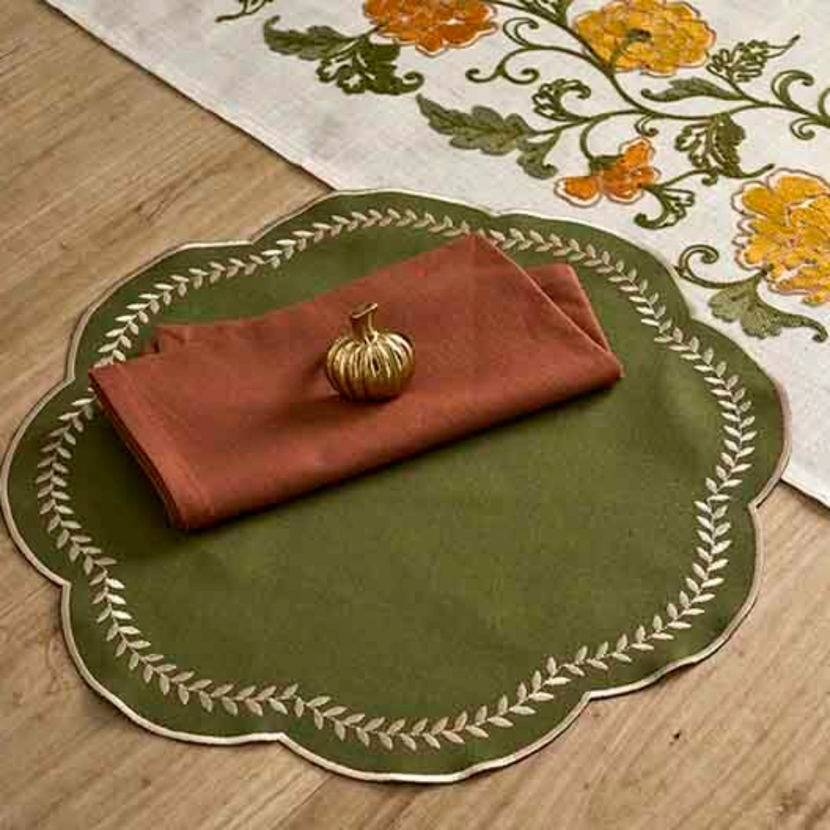 Decorative table setting with a green placemat, red napkin, and floral table runner.