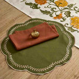 Decorative table setting with a green placemat, red napkin, and floral table runner.