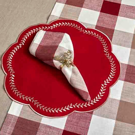Red scalloped placemat with a folded napkin on a checkered tablecloth